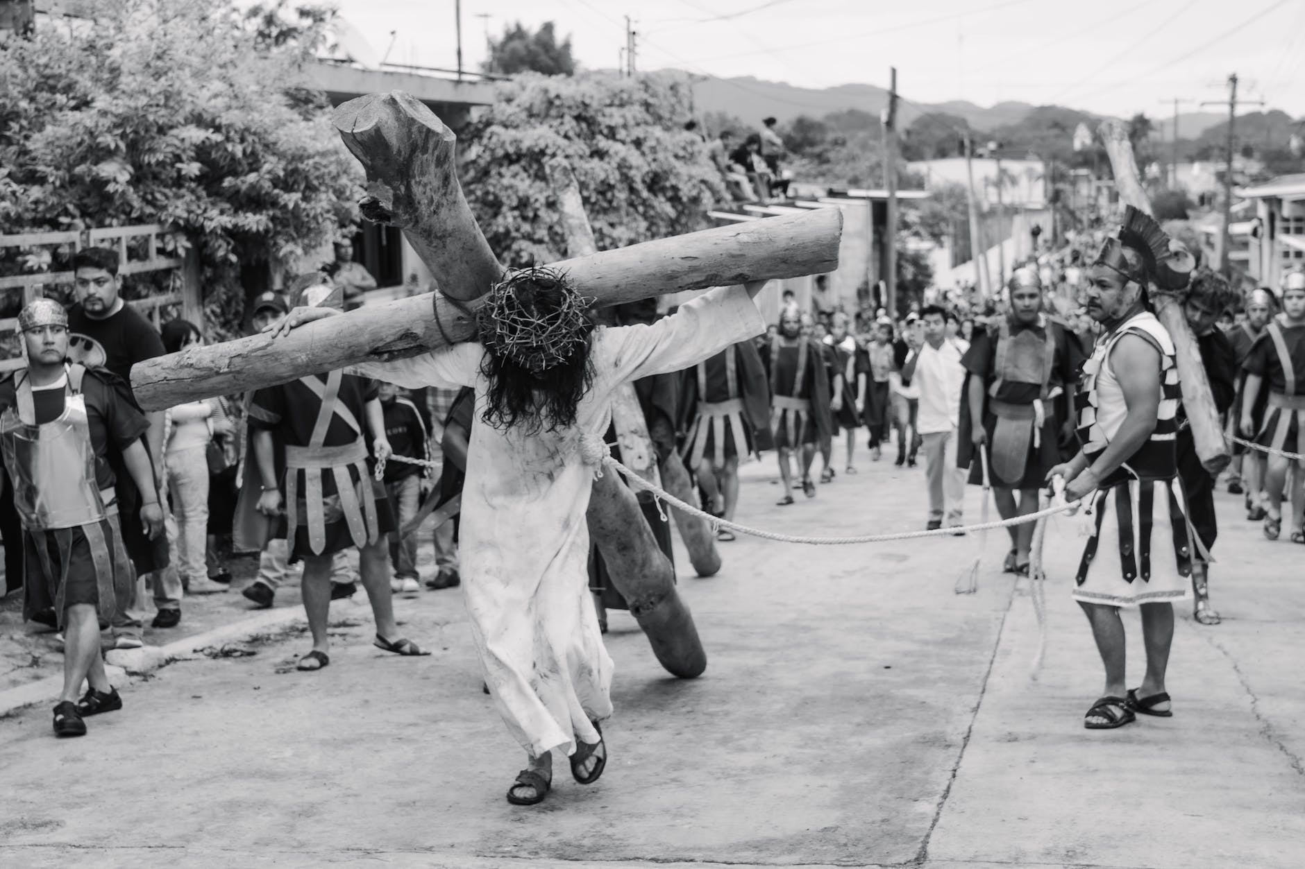 a man carrying wooden cross while walking on the street